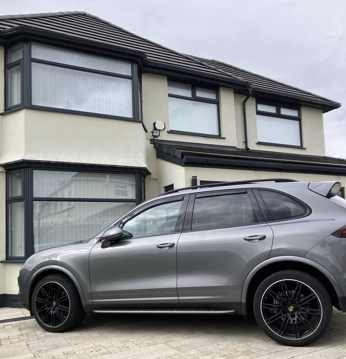 A big grey suburban house and a big grey SUV
